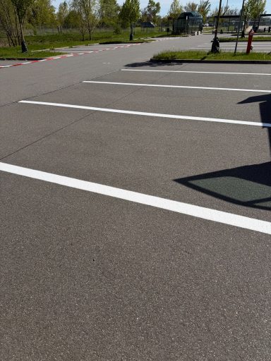 Firmenparkplatz Kabelsketal Leerer Parkplatz mit horizontalen weißen Linien und grüner Umgebung.