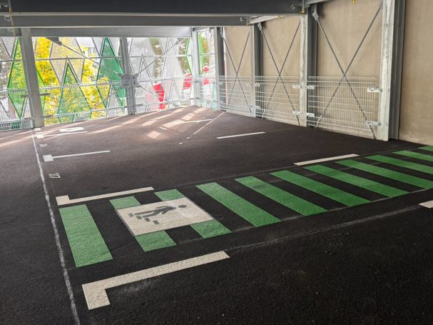 Leerer Parkplatz mit grünen Streifen und klaren Markierungen.