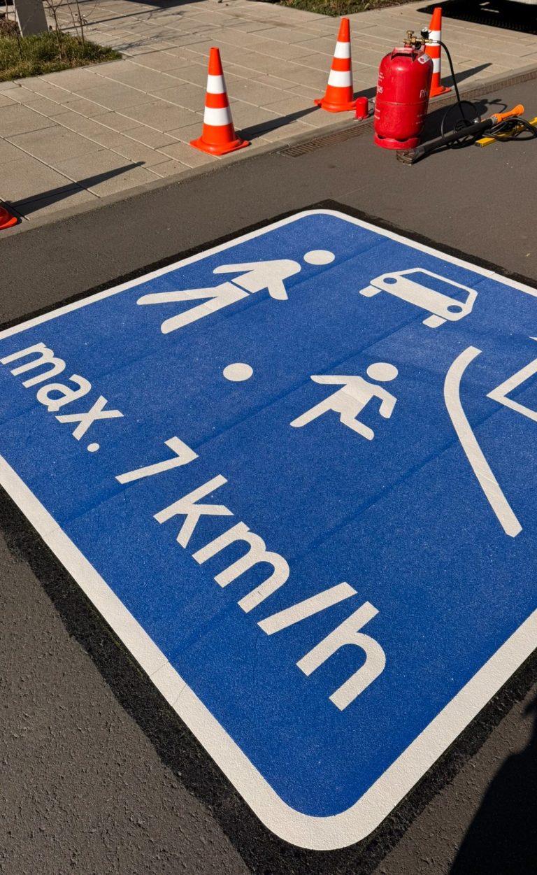 Blaues Verkehrsschild mit max. 7 km/h, Fußgänger- und Fahrzeugbilder