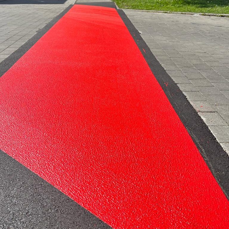 eine rote Fahrradfurt auf einer schwarzen Straße