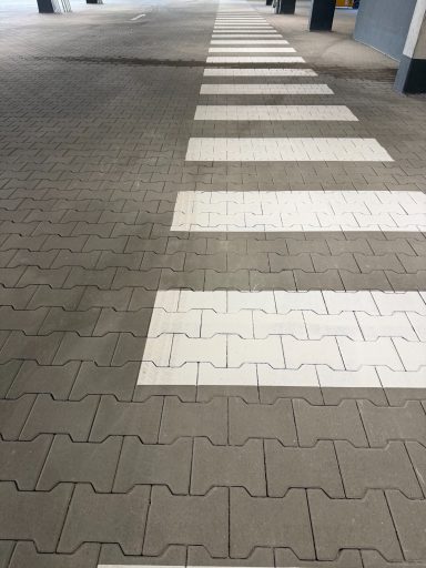 REWE Dippoldiswalde Zebrastreifen auf grauem Pflaster, mit alternierenden weißen und grauen Feldern.