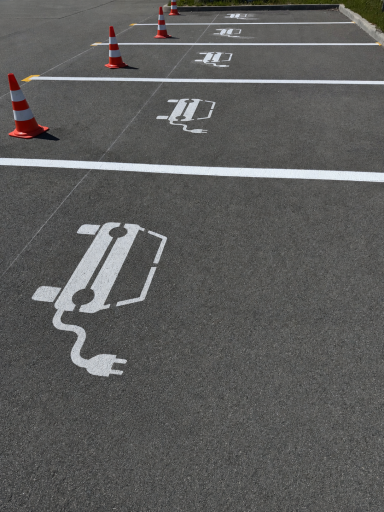 Parkplätze für Elektroautos mit Ladeanschluss und warnenden Pylonen.