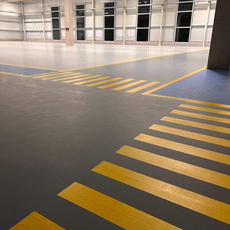 Hallenmarkierung Gelb gestrichene Linien auf grauem Boden in einem leerem, hellen Raum.