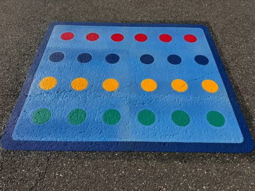 Bunte Bodenmarkierung mit roten, gelben, grünen und blauen Punkten auf blauem Hintergrund.