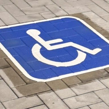 Behindertenparkplatz Behindertensymbol auf blauer Bodenmarkierung.