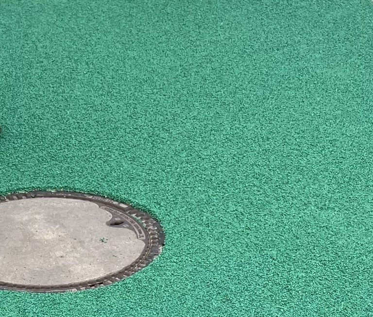 Grüne Epoxidharzbeschichtung mit einer runden, grauen Metallplatte.