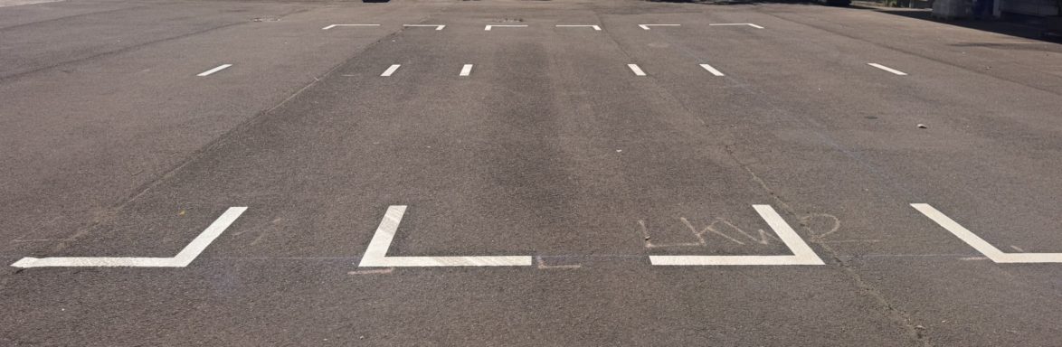 Leere Parkfläche mit weißem Markierungen auf asphaltiertem Boden.