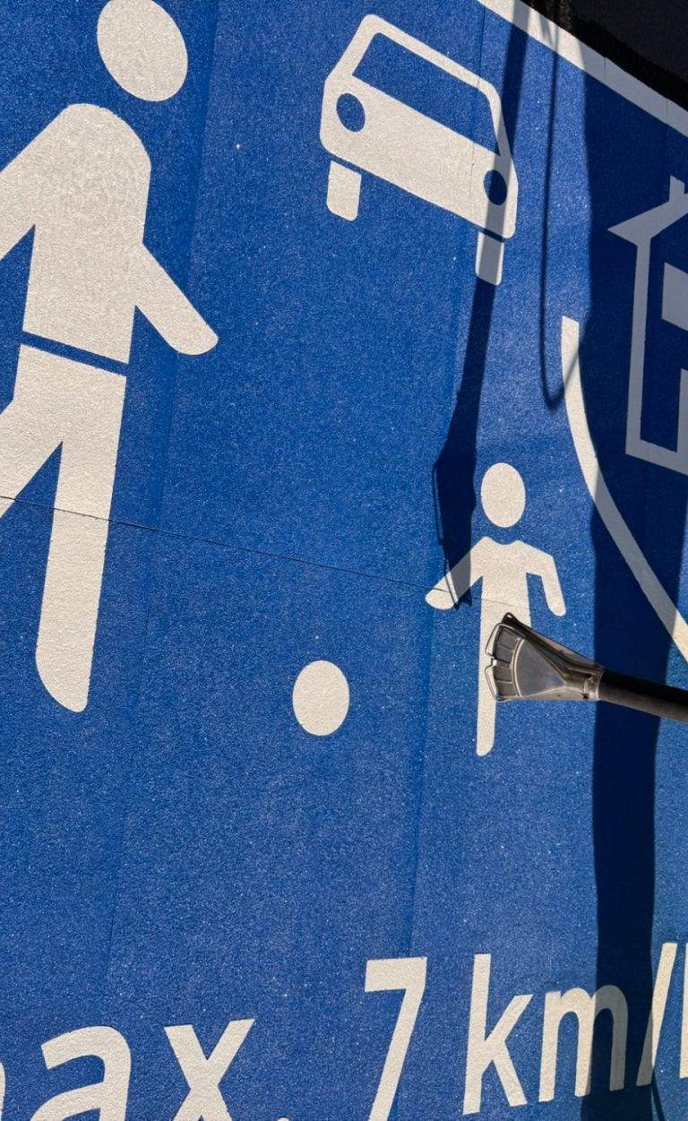 Verkehrsschild mit Fußgänger- und Fahrzeugsymbolen, Geschwindigkeitsbegrenzung 7 km/h.