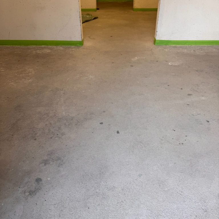 Boden in einem Raum mit grauem Estrich und grünen Wänden.