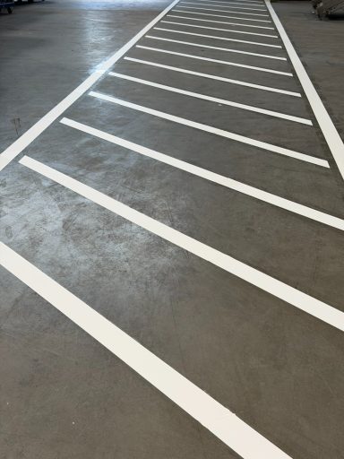 weiße Querstreifen auf einem grauen Hallenboden