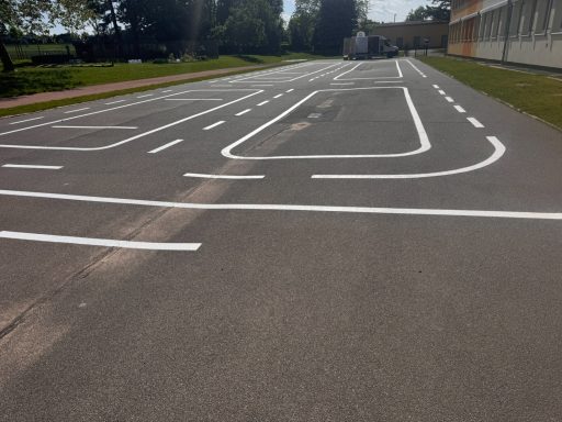 Grundschule Mohorn Leere Asphaltfläche mit weißen Fahrbahnmarkierungen und Kurven.