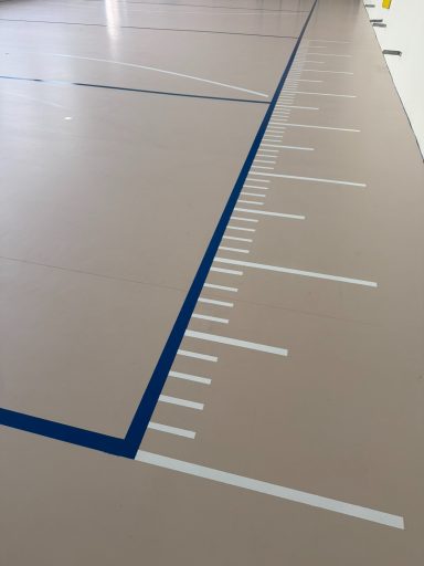 heller Sportboden mit kurzen und langen weißen Strichen als Maßband